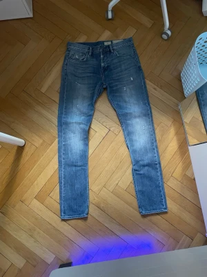 Blå raka jeans i klassisk modell - Säljer ett par blå jeans med raka ben och klassisk femficksdesign. Jeansen har en snygg tvättad look och normal passform, perfekta till vardagsstilen. Materialet är slitstarkt denim i bomull. W30