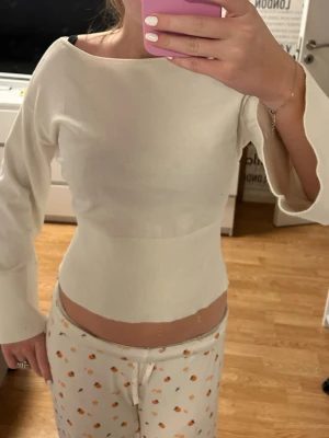 Vit ribbad topp med vida ärmar - Säljer en stilren vit topp med ribbad midja och långa, vida ärmar. Toppen har en bred, båtringad hals och är tillverkad i ett mjukt, stretchigt material som sitter tajt över kroppen. Endast använd 2 gånger!