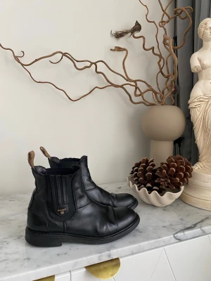 GANT svarta Chelsea boots stl 39 – fint skick - Säljer ett par svarta Chelsea boots från GANT i storlek 39. Skorna är använda men i fint skick och redo för många fler tillfällen. Den klassiska, stilrena designen gör dem perfekta både på kontoret, på AW, middag eller en promenad i stan. Bekväma att bära hela dagen, och samtidigt snygga nog att lyfta vilken outfit som helst. Tidlösa GANT Chelsea boots med stil och komfort som håller länge.  