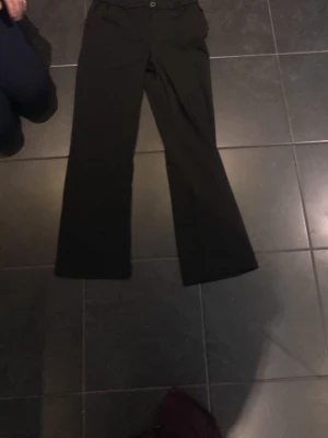 Svarta bootcut kostymbyxor - Snygga svarta kostymbyxor med bootcut passform. Byxorna har klassisk midja och stängs med knapp och dragkedja. Perfekta till en stilren look och passar till många olika outfits.
