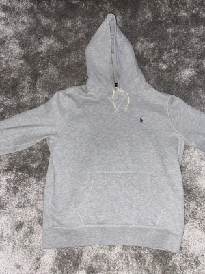 Grå hoodie från Polo Ralph Lauren - Snygg grå hoodie från Polo Ralph Lauren med klassisk blå logga broderad på bröstet. 