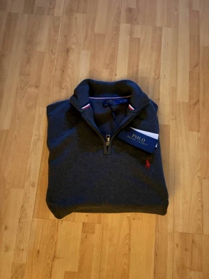 Ralph lauren quarterzip mörkgrå Ny-oanvänd - Säljer en helt ny och oanvänd Ralph Lauren quarter zip i stilren mörkgrå färg. Tidlös design med dragkedja i halsen och diskret broderad Ralph Lauren-logga på bröstet. Tröjan är tillverkad i hög kvalitet med mjukt och bekvämt material – perfekt för både vardag och mer uppklädda tillfällen. 🔹 Märke: Ralph Lauren 🔹 Modell: Quarter zip 🔹 Färg: Mörkgrå 🔹 Skick: Helt ny / oanvänd 🔹 Passform: Klassiskl Nypris är högt – perfekt chans att fynda. Hör gärna av dig vid frågor eller om du vi