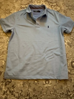 Ljusblå pikétröja från Ralph Lauren - Klassisk ljusblå pikétröja från Ralph Lauren med broderad logga på bröstet. Tröjan har korta ärmar. Inga defekter finns, inget fast pris. Hör av er vid minsta fundering 