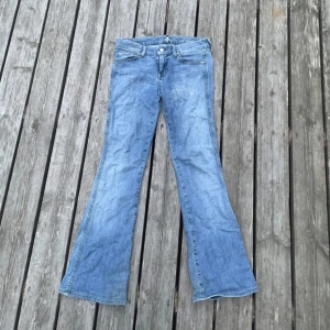 Blå bootcut jeans från Seven for all mankind - Snygga ljusblå bootcut jeans från  med klassisk femficksdesign och broderade detaljer på bakfickorna. Jeansen har låg midja och är tillverkade i mjukt denimtyg som ger en avslappnad vibe. Använt fåtal ggr