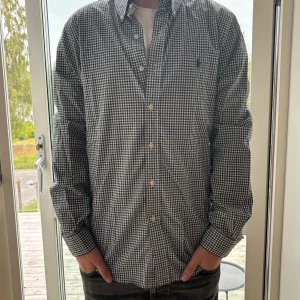Rutig skjorta från Ralph Lauren M - Snygg rutig skjorta från Ralph Lauren i slim fit-modell. Skjortan har blått och grönt rutmönster, klassisk krage med knappar och broderad logga på bröstet. Tillverkad i mjuk bomull och har långa ärmar. Perfekt för dig som gillar stilrena och tidlösa plagg.