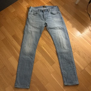 Lee Luke ljusblå jeans W30 L32 - Säljer ett par Lee Luke jeans i ljusblå tvätt med klassisk femficksdesign. Jeansen har smal passform och raka ben, tillverkade i bomull. Perfekta för dig som gillar en clean och stilren look.