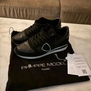 Philipe model trainers svart + påse och snören - Säljer dessa svarta phillipe model skor som är i väldigt bra skick. Dem är knappt använda. Man får med snörerna+påsen som kommer till. Om ni har frågor är det bara att skriva!