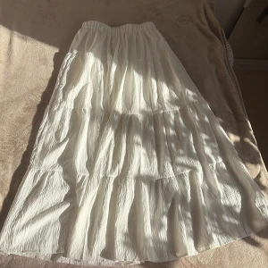 Vit långkjol med volanger -  Långkjol med flera volanglager och resår i midjan för perfekt passform. Den är lätt, luftig och har en krinklad struktur som ger en trendig och avslappnad look – perfekt för varma dagar eller en bohemisk stil ✨  💸 Säljer billigt & brukar acceptera prisförslag – kika gärna på mina andra annonser för fler fynd! 📦 Snabb leverans & rökfritt hem. 