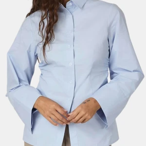 Blå skjorta med vida ärmar från Neo Noir - Snygg ljusblå skjorta från Neo Noir med klassisk krage och knappar framtill. Skjortan har vida, långa ärmar och en lätt utsvängd passform. Storlek M. 