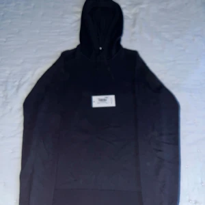 Mörkblå stickad hoodie från RYVLS - Snygg mörkblå stickad hoodie från RYVLS Stockholm. Tröjan har huva med snörning och är tillverkad i ett mjukt stickat material. Perfekt för dig som gillar en clean och stilren look med en twist. Passar dig som vill ha en hoodie med lite mer känsla.