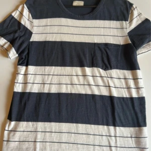 Randig t-shirt från Selected Homme - Snygg t-shirt från Selected Homme i marinblått och vitt med breda och smala ränder. Klassisk rund halsringning och en bröstficka på vänster sida. Tillverkad i mjuk bomull, perfekt för en avslappnad stil.