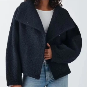 Mörkblå teddyjacka med oversized krage - Mysig mörkblå teddyjacka med stor, bred krage och avslappnad passform. Jackan är tillverkad i ett fluffigt teddy-material och har en oversized look som ger en cool vibe. Perfekt att slänga på sig över en hoodie eller t-shirt för en trendig stil.