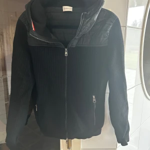 Svart stickad jacka från Moncler - Skit snygg jacka från moncler perfekt till hösten. Jackan är i ett bra skick förutom ett hål vid armhålan, skriv för bild. Går lätt att laga och därför det låga priset. Hör av er för frågor eller funderingar!🙌🏻