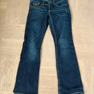 Blå bootcut jeans från Gina Tricot Young modellen heter ”chunky Low flare jeans”  - Snygga mörkblå jeans från Gina Tricot Young i storlek 152. Modellen är bootcut med kontrastsömmar och klassiska fickor både fram och bak. Jeansen har låg midja och är tillverkade i mjukt och stretchigt denimtyg. Modellen heter chunky Low flare jeans. Byxorna är även något slitna nedtill ena benet.