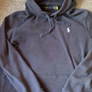 Ralph Lauren Hoodie - Snygg stickad Ralph Lauren hoodie i storlek S! Passar 170-180 ungefär, sitter lite kort på mig där bak som är 180. Skick 8/10 utan defekter förutom en MINIMAL öppning i tyget som ni ser på sista bilden men det syns varken med ögonmått eller knappt med kamera!