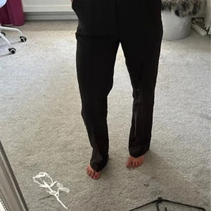 Svarta kostymbyxor från Madlady - Säljer ett par svarta kostymbyxor från Madlady i storlek 38. Byxorna har rak passform och klassisk look, perfekta för en clean och stilren outfit. Materialet känns mjukt och följsamt, och de har en snygg midja som sitter bekvämt.