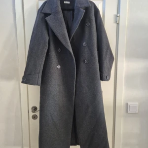 Grå lång kappa från Cubus, storlek XS - Säljer en stilren grå kappa från Cubus i storlek XS. Kappan är lång, har dubbelknäppning med stora knappar och bred krage. Klassisk modell som passar till många outfits. Använd 2 gånger. Nypris 1400:-