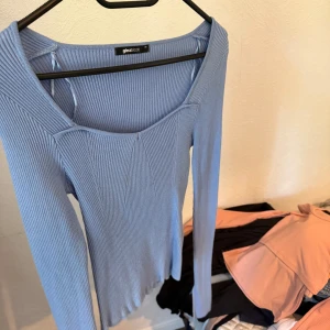Ljusblå ribbad topp från Gina Tricot - Säljer en ljusblå långärmad topp från Gina Tricot. Toppen är ribbad med en snygg, något fyrkantig urringning och figurnära passform. Perfekt att styla med jeans eller kjol för en trendig look.
