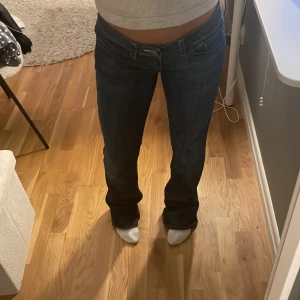 Mörkblå Replay bootcut jeans - Säljer ett par mörkblå jeans från Replay med bootcut-modell och låg midja. Jeansen har klassiska fickor och snygga detaljer på bakfickorna. Perfekta om du gillar en lite vidare passform nertill och vill ha en cool, avslappnad look.