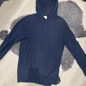 Mörkblå 100% kashmirhoodie från John Henric - Säljer en stilren mörkblå hoodie från John Henric i kashmir. Nypris 1800. Storlek L men passar S eller M skulle jag säga. Litet märke/hål mellan snörerna (se bild 2) därav priset.