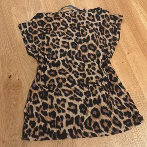 Leopardmönstrad tröja - Snygg tröja från lager 157 ”livia” med leopardmönster i bruna och svarta toner. Modellen är ärmlös med rund halsringning och har en  passform som framhäver kroppens former. Perfekt för dig som vill sticka ut med ett djurmönster och gillar trendiga detaljer.