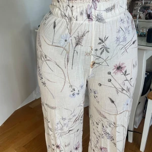 Blommiga vida byxor från H&M XS - Superfina ljusa byxor från H&M i storlek XS med blommigt mönster.. Byxorna har resår i midjan och är vida i modellen, perfekta för en chill och somrig look. Materialet är mjukt och luftigt. Passar S&M