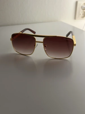 Solglasögon - Snygga solglasögon. Glasen är bruna med tonad effekt och skalmarna har gulddetaljer samt bruna ändar. Perfekt accessoar för en trendig look.