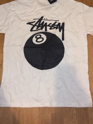 Vit Stüssy t-shirt med 8-ball print storlek M - Helt ny Vit t-shirt från Stüssy med svart 8-ball print storlek M fraktar första samma dag eller dagen efter 