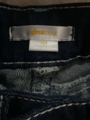 Mörkblå jeans från Gina Tricot - Snygga mörkblå jeans från Gina Tricot i klassisk modell. Jeansen har utsvängda ben och normal passform, perfekta till många olika stilar. Tillverkade i slitstarkt denimtyg med klassiska sömmar och midja.