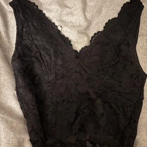 Svart spetslinne - Säljer ett elegant svart spetslinne med v-ringad design.💗🥰