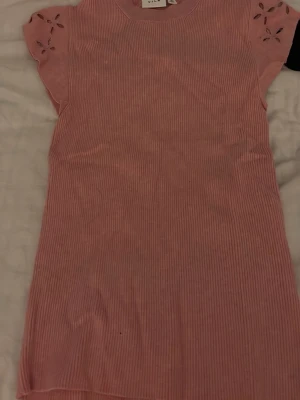 Rosa och svart ribbad topp från Vila - Två toppar från Vila, en i ljusrosa och en i svart. Båda har ribbad struktur, korta ärmar med broderade detaljer och rund halsringning. Perfekta för dig som gillar en enkel men söt stil. Aldrig använda 