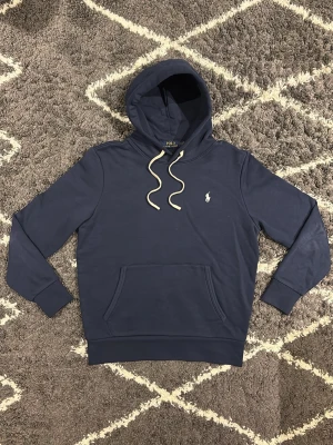  Polo Ralph Lauren blue Hoodie - Mörkblå hoodie i ny skick. Skön passform och enkel stil som funkar till allt. Jag väger 70KG och är 180CM och den passar mig perfekt. 