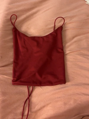 Röd croppad linnetopp med snörning - Röd croppad linnetopp med tunna axelband och snygg snörning i ryggen. 