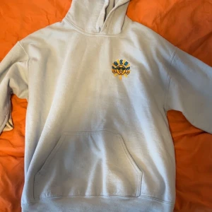 Ljusgrå hoodie med tryck Summertime - Ljusgrå hoodie från Greens med färgglatt tryck på bröstet och stort motiv på ryggen med texten 'Summertime'. Hoodien har huva och en stor magficka. Perfekt för dig som gillar streetwear och unika prints. Materialet känns mjukt och bekvämt.