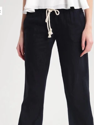 Svarta linnebyxor med snörning från Roxy - Snygga svarta linnebyxor med avslappnad passform och vit snörning i midjan. Perfekta för varma dagar och ger en chill vibe till din outfit. Byxorna har raka ben och är tillverkade i mjukt linne. Från Roxy strl xs/ s. Säljer för att jag aldrig använder 