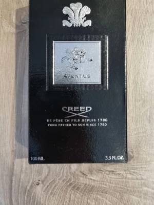 Creed Aventus Eau de Parfum 100ml 97% Använd - Lyxig parfym i en elegant svart förpackning med silverdetaljer och klassisk logotyp. Flaskan rymmer 100 ml och doften är känd för sin exklusiva och tidlösa karaktär. Perfekt för dig som vill ha något unikt och ikoniskt. Kontakta mig gärna vid köp + eventuella frågor. Tack!