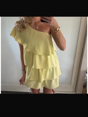 Gul volangklänning  - Gul volangklänning med en arm från Zara i stl S. Jag köpte den begagnad men endast använd en gång av mig! De är en gammal modell från Zara som inte säljs längre och denna är i väldigt fint skick därav priset! Välkomna med bud men skambud undanbedes!