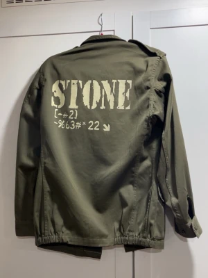Olivgrön fieldjacket från WAREIN - Säljer en olivgrön militärinspirerad jacka från WAREIN, modell från Lille 1987. Modellen är lite tajt i sig, skulle därför säga S/M. Jackan har stora fickor framtill och tryck med texten 'STONE' på ryggen. Stängs med knappar. Säljer den då den är för liten. Jackan är ganska använd men har inga defekter. Hör av er vid frågor✌️