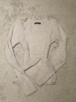 Beige stickad tröja från Gina Tricot - Mysig beige stickad tröja från Gina Tricot med rund halsringning och långa ärmar. Tröjan har ribbade muddar vid ärmslut och nederkant, perfekt för lager på lager under kyliga dagar.