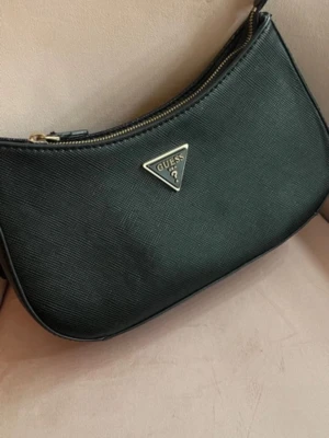 Svart axelväska från Guess - Guess handväska, bra skick förutom att ena bandet har gått av på väskan man får med metalbiten om man är händig går det att fixa snabbt. Annars kan man hålla den med bara ena sidan som på bilden. Orginalpris 1200kr