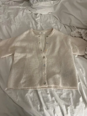 Beige ribbad kofta från Gina Tricot - Superfin beige kofta från Gina Tricot i ullmix. Kortare modell med ribbad struktur, rund halsringning och knappar framtill. Perfekt att slänga över en topp för en chill look. Passar dig som gillar mjuka och mysiga plagg. Endast använd 1 gång