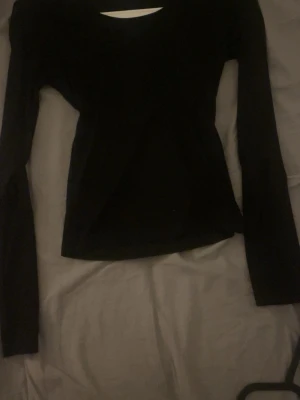 Svart långärmad topp - Säljer en svart långärmad topp Toppen har en slim passform och är tillverkad i ett stretchigt material som sitter snyggt på kroppen. Perfekt att styla med jeans eller kjol för en trendig look.