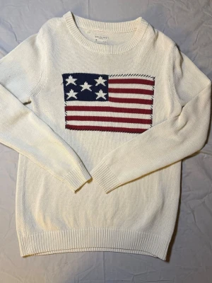 Selected Homme tröja beige/vit – USA-flagga – Strl S – Mycket fint skick - Säljer en Selected Homme tröja i beige/vit färg, storlek Small, i mycket fint skick. Har en snygg USA-flagga på magen som ger en sportig och retro vibe.  Perfekt för casual outfits, laidback stil eller vintage-inspirade looks.  Mått: Undersida: 44 cm Längd: 73 cm  • Märke: Selected Homme • Storlek: S • Skick: Mycket fint  Selected Homme 1