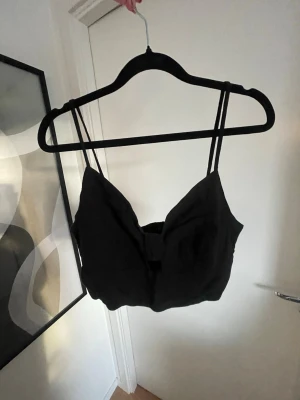 Svart croppad linnetopp med cut-out - En svart croppad linnetopp med tunna axelband och en snygg cut-out detalj framtill