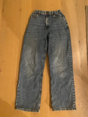 Blå jeans från Lindex - Säljer ett par klassiska blå jeans från Lindex i storlek 152. Jeansen har rak passform, justerbar insida för extra komfort. Tillverkade i slitstarkt denim med fem fickor och bälteshällor. Perfekta till vardagslooken!