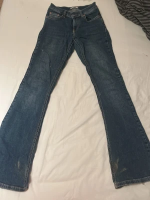 Blå bootcut jeans från Perfect Jeans - Säljer ett par klassiska blå bootcut jeans från Perfect Jeans i storlek 34. Jeansen har fem fickor, snygga kontrastsömmar och en bootcut passform som ger en retrovibe. Materialet är slitstarkt jeans och färgen är mörkblå med lätt tvättade detaljer. Dom tvättas sjävklart innan dom postas!!