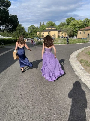 Balklänning  - Säljer min lila balklänning från JJ's House med tunna justerbara axelband, v-ringning och paljettspets upptill. Den har en hög slits på ena sidan och sitter så fint runt midjan. Perfekt till bal eller student!💜Materialet är lätt och färgen heter Tahiti på deras hemsida, en superfin lila färg. Endast använd en gång, riktigt bra skick😊 Nypris: 1842kr Mitt pris: 1500kr 