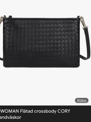 Svart flätad axelväska från Åhléns - Säljer en svart flätad axelväska från Åhléns med stilren design och justerbar axelrem. Väskan har ett elegant flätmönster och är tillverkad i skinnimitation. Perfekt för dig som vill ha en snygg och praktisk väska till vardagen.