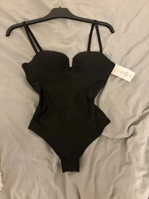 Hm body - Supersnygg och eftertraktad body från H&M i klassisk svart. Modellen är slutsåld i butik och har varit väldigt populär. Endast testad, i mycket fint skick, lapp och allt kvar. Säljer pga den var för liten för mig.  Bodyn har inbyggda kupor som ger bra stöd och en smickrande form, samt justerbara axelband för perfekt passform. Designad som string, vilket gör den perfekt både under kläder eller att bära som den är lika snygg till jeans som till kjol eller kostymbyxor. Skriv om du har några frågor🥰