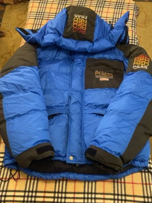 Blå Peak Performance dunjacka S - Säljer en blå och svart dunjacka från Peak Performance med broderad logga på bröstet och huvan. Jackan har dragkedja, stora fickor och justerbar huva. Perfekt för kalla dagar och riktigt snygg streetstil.